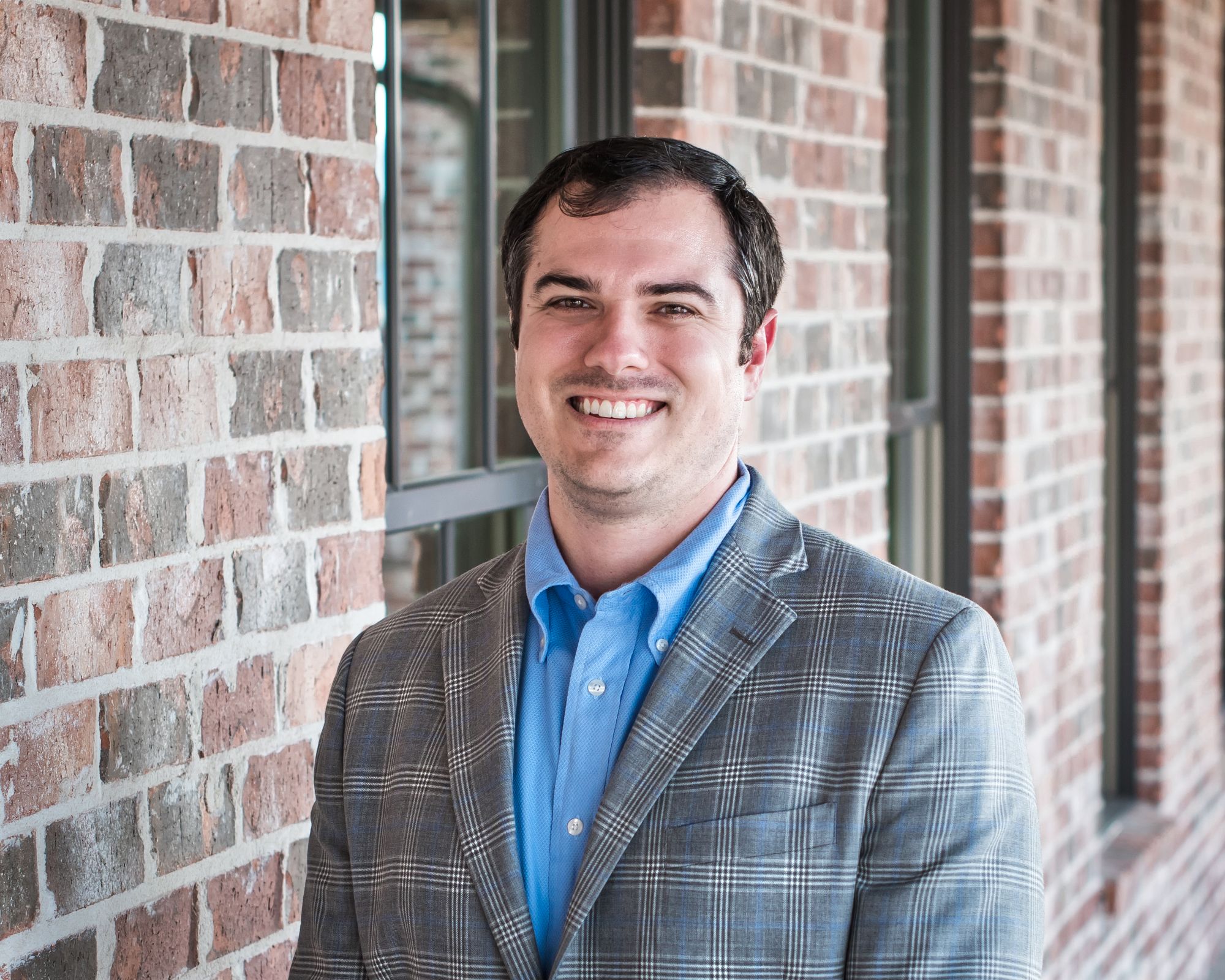 Dr. Barry Benton, board-certified orthodontist at Designer Smiles by Benton, smiling in front of a brick wall